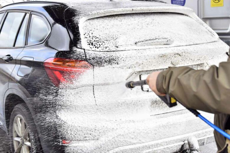 Lavage d'une voiture avec une mousse de nettoyage pour faire glisser les saletés.