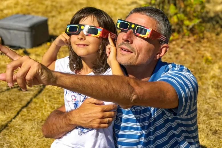 Un père et son enfant observant une éclipse avec des lunettes de protection.