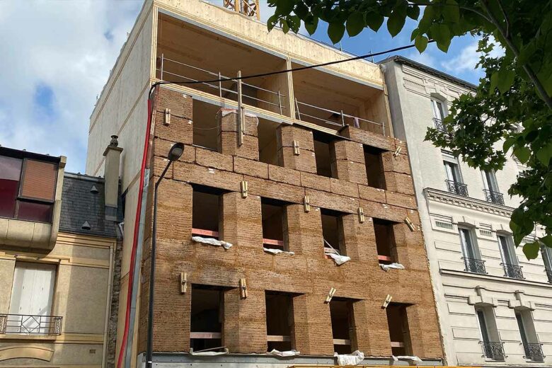 Façade réalisée avec des blocs de construction en terre crue pour un immeuble de 4 étages.