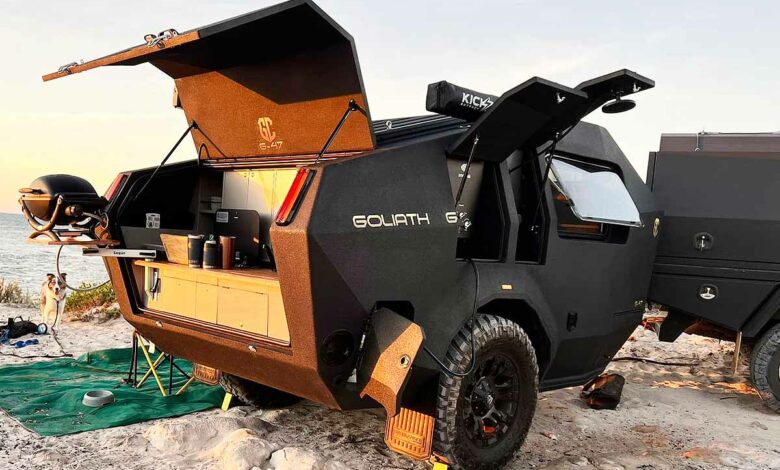Une caravane dotée d'une cuisine extérieure avec barbecue et d'une douche.