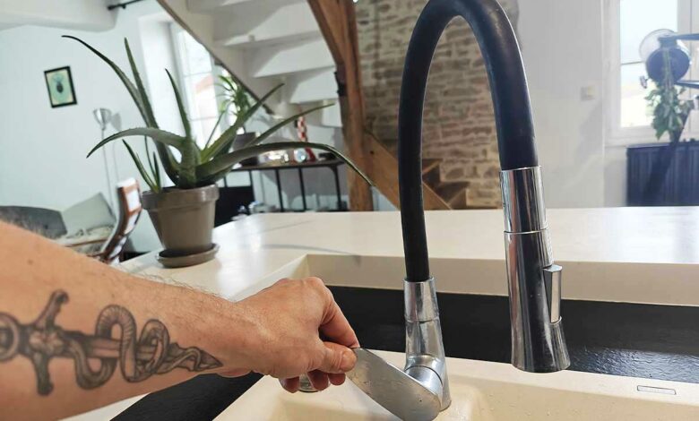 Un homme qui ouvre un robinet pour faire couler de l'eau.