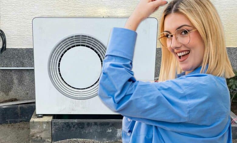 Une femme victorieuse devant une pompe à chaleur.