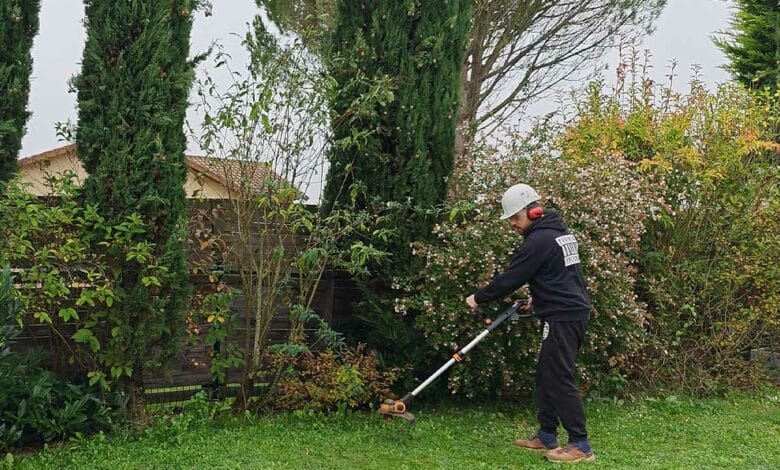 Un homme débroussaille son jardin.