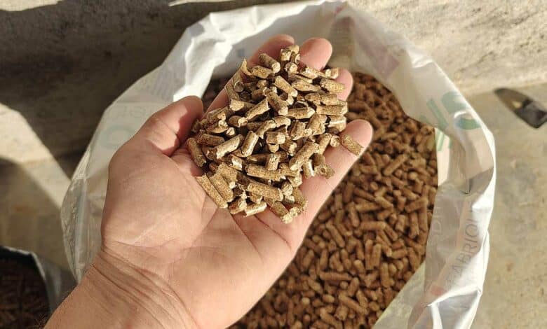 Une main qui tient des pellets au-dessus d'un sac ouvert.