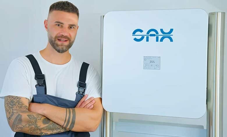 Un technicien à côté d'une batterie résidentielle Sax Power.