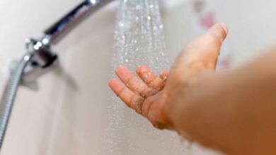 Une main vérifie la température de l'au de la douche.