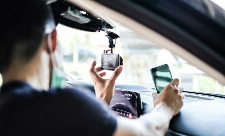 Un homme installe une dashcam dans un véhicule.