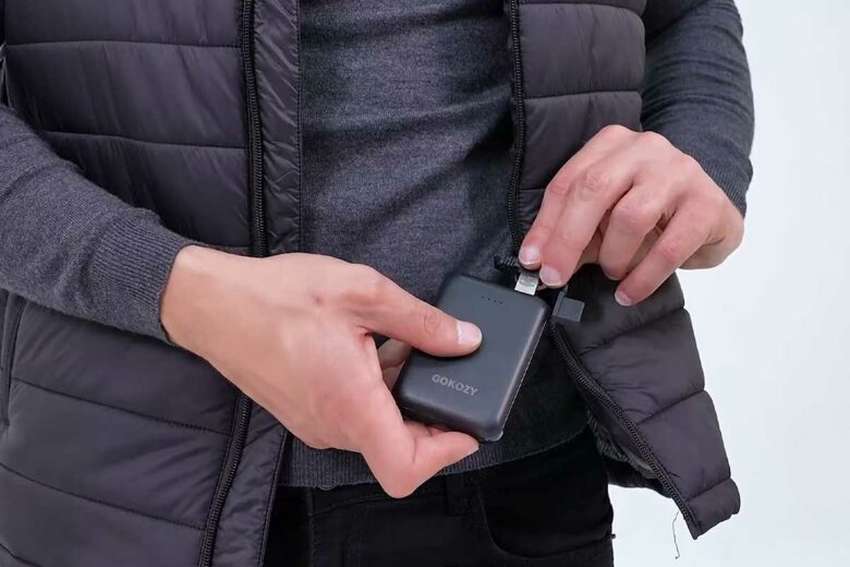 Un homme branche la batterie de sa veste chauffante.