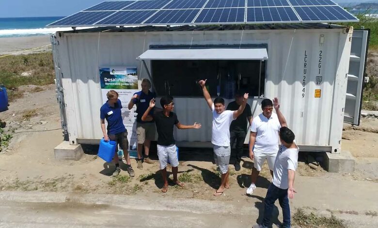 Des personnes devant une structure de dessalement qui fournit de l'eau potable.