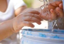 Un enfant les mains sous l'eau.