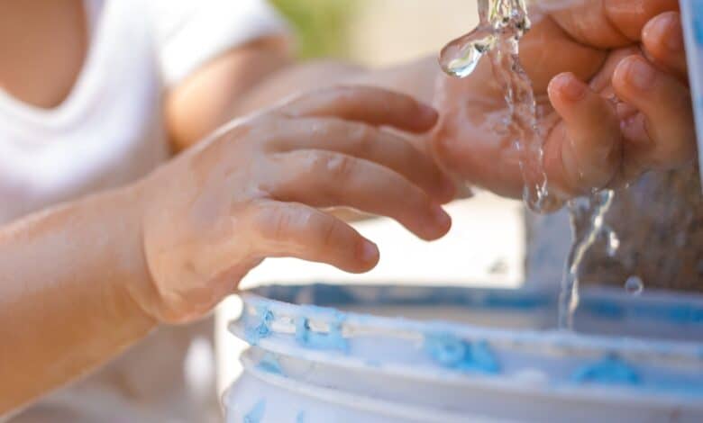 Un enfant les mains sous l'eau.