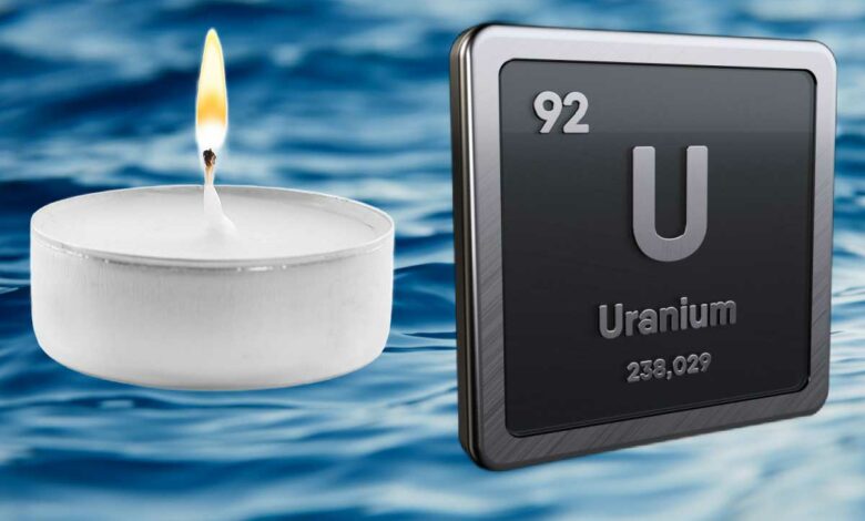 Une bougie et le symbole chimie de l'uranium sur fond d'océan.
