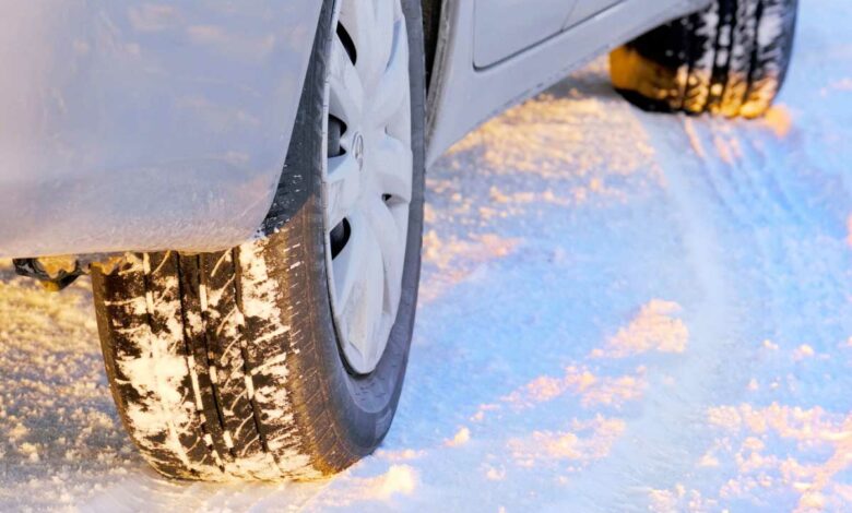 Une voiture circule sur une route enneigée.