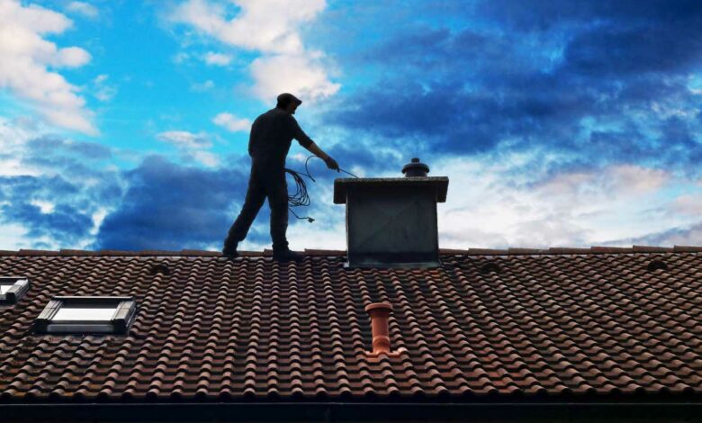 Un homme sur le toit d'une maison pour le ramonage.