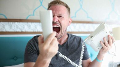 Un homme très énervé qui hurle sur le combiné téléphonique.