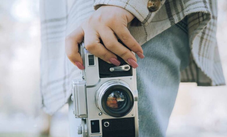 Une femme tient un appareil photo.