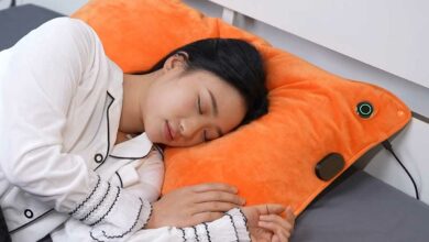 Une femme dort sur un oreiller muni d'un système chauffant et anti-ronflement.