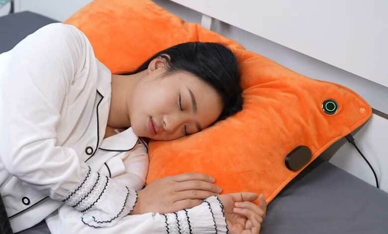 Une femme dort sur un oreiller muni d'un système chauffant et anti-ronflement.
