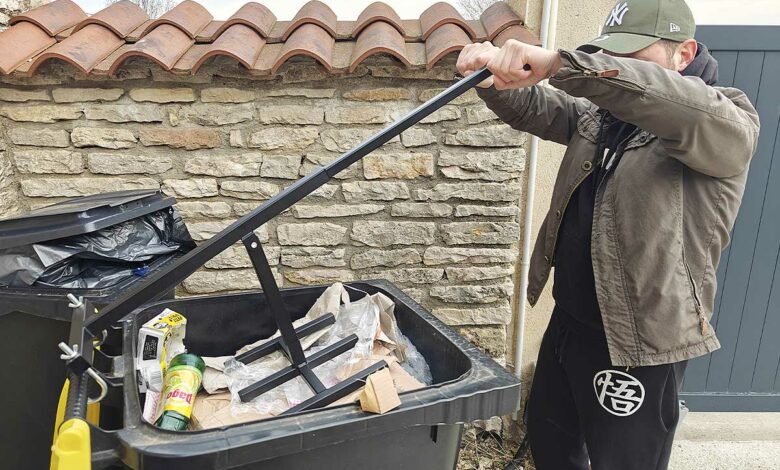 Un homme compacte ses poubelles pour réduire leur volume.