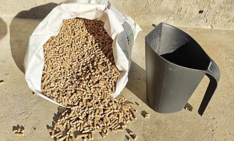 Une pelle à pellets à côté d'un sac de granulés.