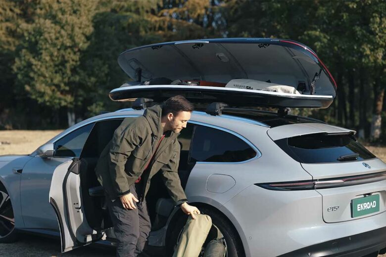 Un homme range des bagages dans un coffre de toit.