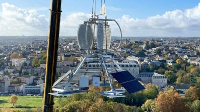 Une éolienne déplacée par une grue pour son installation sur un toit d'immeuble.