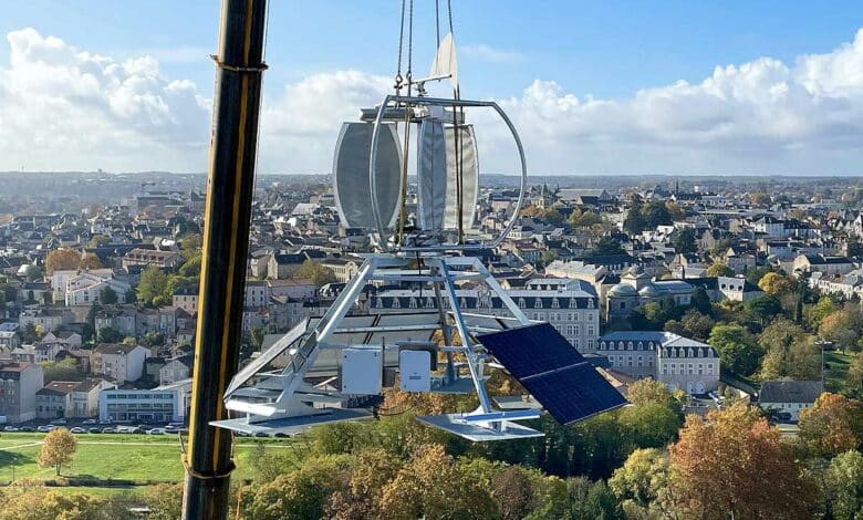 Une éolienne déplacée par une grue pour son installation sur un toit d'immeuble.