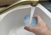 Une personne se sert un verre d'eau au robinet.