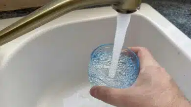 Une personne se sert un verre d'eau au robinet.