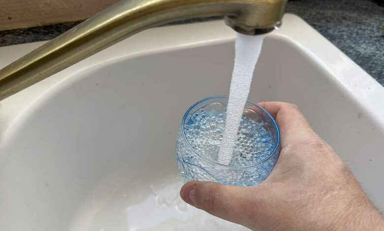 Une personne se sert un verre d'eau au robinet.