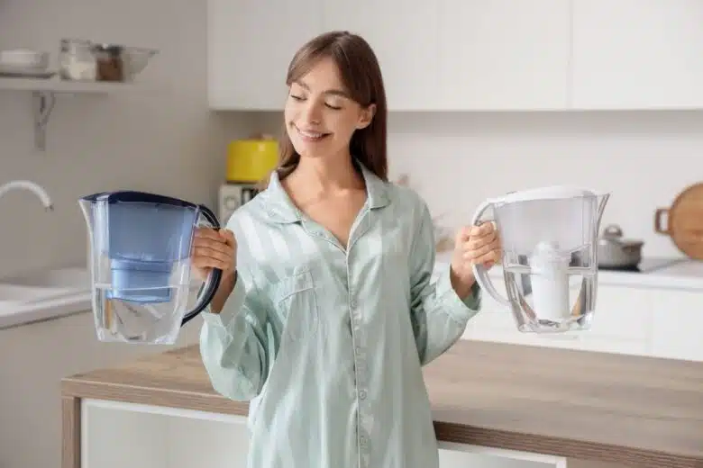 Une femme tient deux carafes filtrantes pour l'eau.