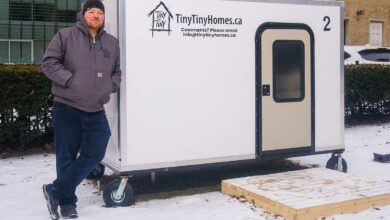 Un homme se tient contre une tiny house.
