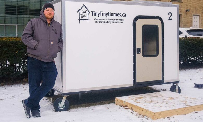 Un homme se tient contre une tiny house.