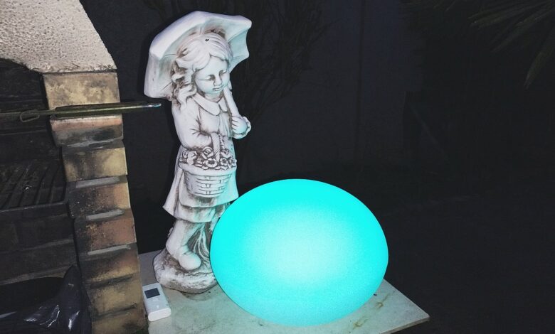 Le Galet GuirLED illumine l’extérieur avec une belle lumière bleue, posé près d’une statue sous un parapluie.
