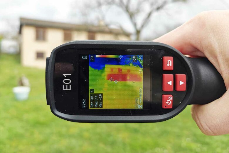 Une personne utilise une caméra thermique pour détecter des problèmes d'isolation.