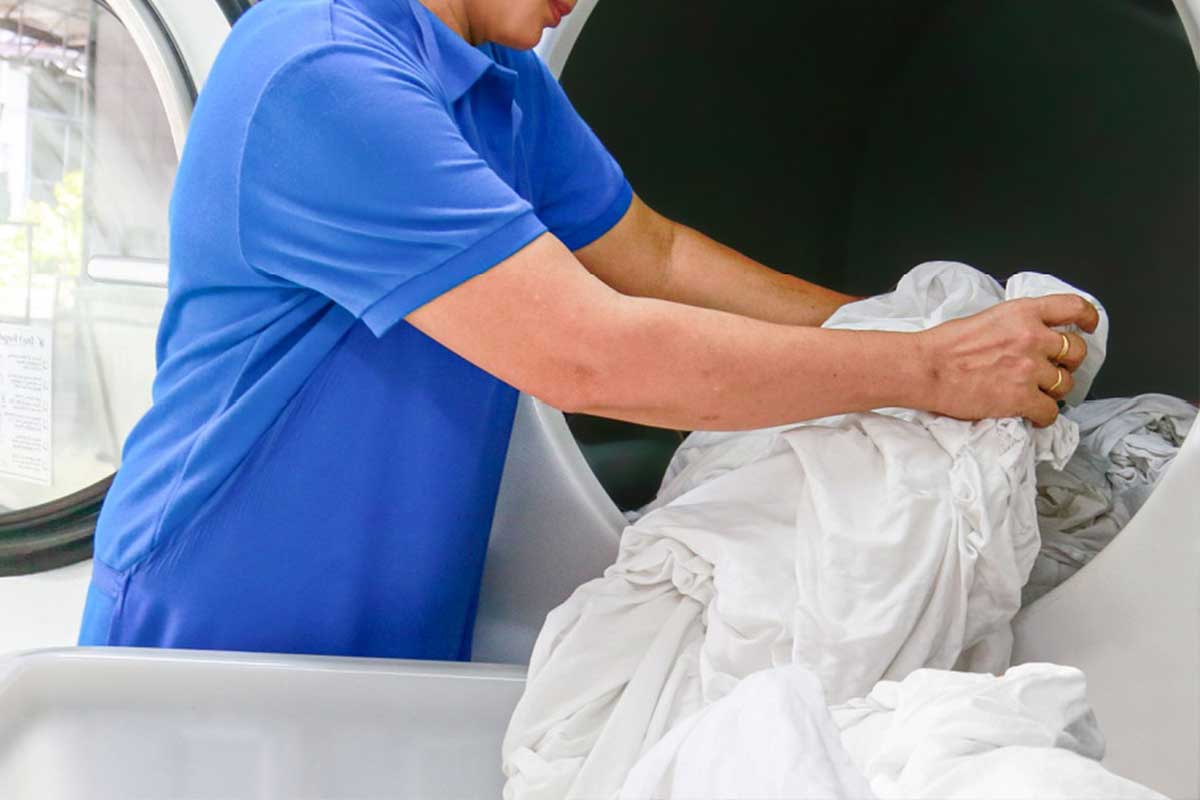 Une femme s'occupe du linge dans une blanchisserie.