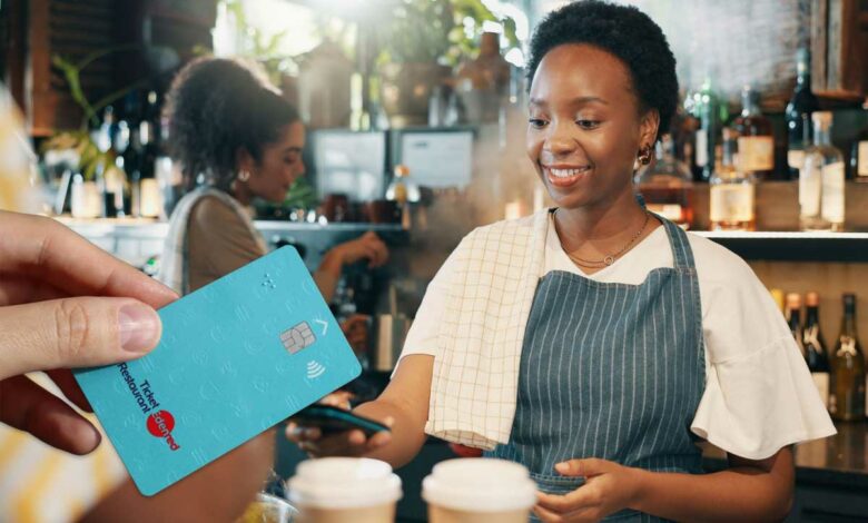 Une personne paie la note avec sa carte ticket resto.