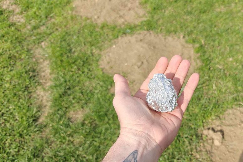 Une boule de papier aluminium tenu au-dessus d'une galerie de taupe.