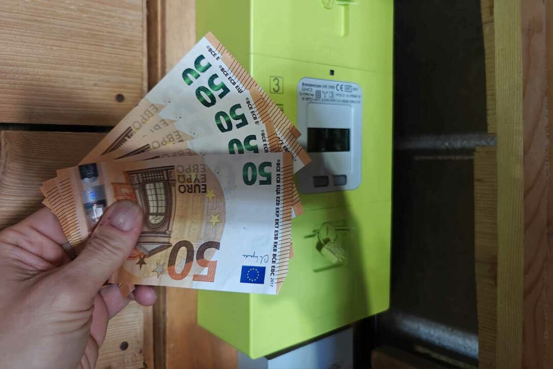 Un compteur Linky et une main tenant des billets.