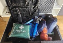 Un kit d'urgence avec une trousse de soins, des gourdes filtrantes, un panneau solaire et un couteau de survie.