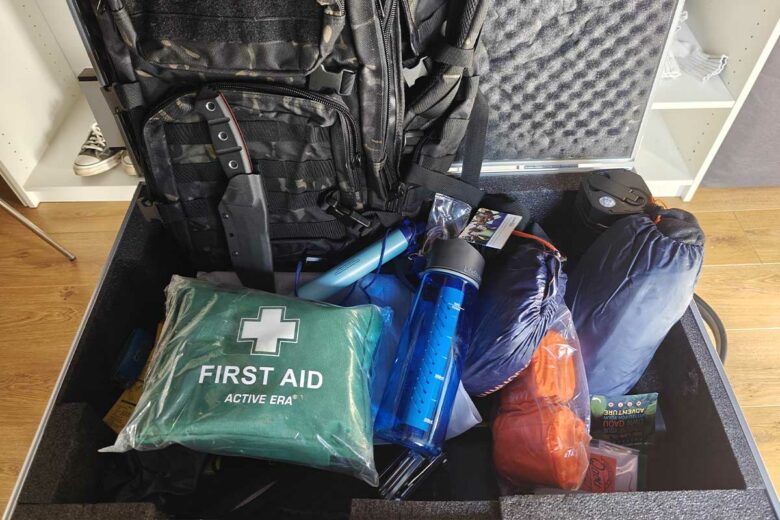 Un kit d'urgence avec une trousse de soins, des gourdes filtrantes, un panneau solaire et un couteau de survie.