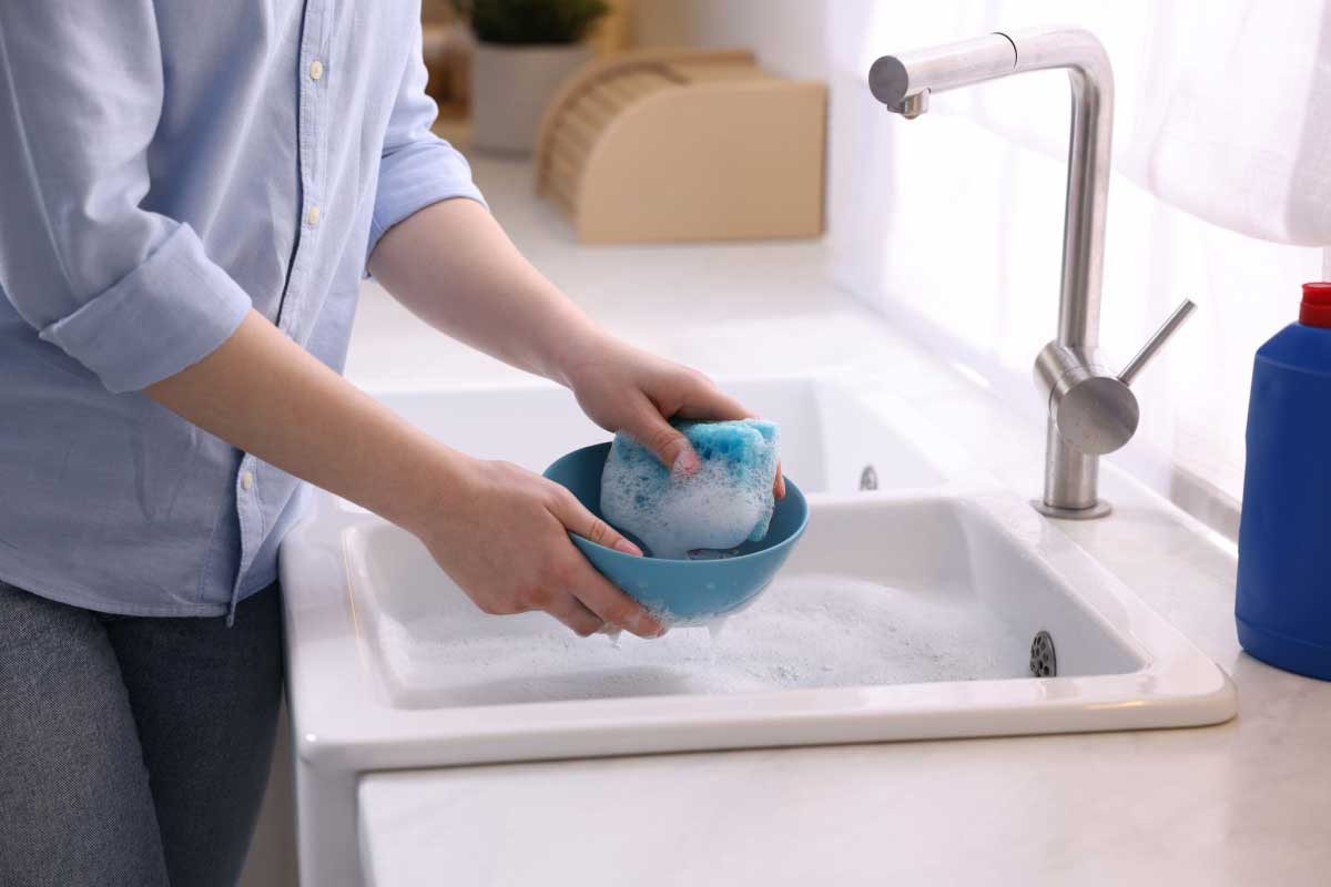 Une personne fait la vaisselle à la main.