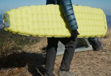 Un homme porte son matelas gonflable.