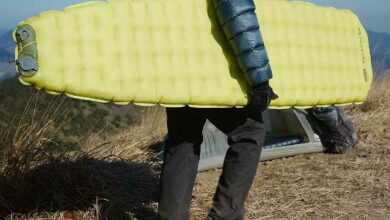 Un homme porte son matelas gonflable.