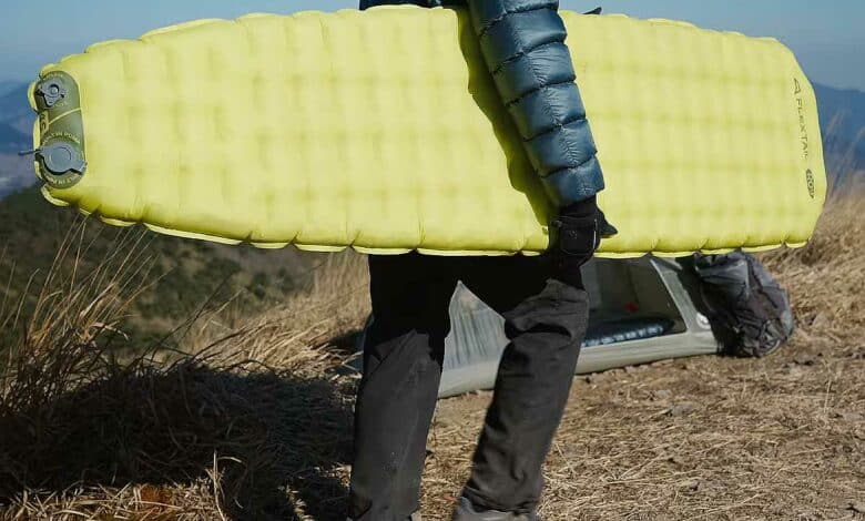 Un homme porte son matelas gonflable.