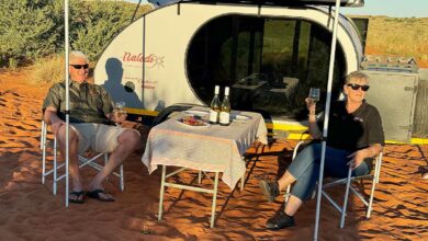 Un couple dine près de sa caravane.