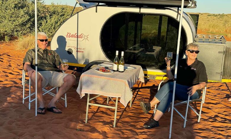 Un couple dine près de sa caravane.