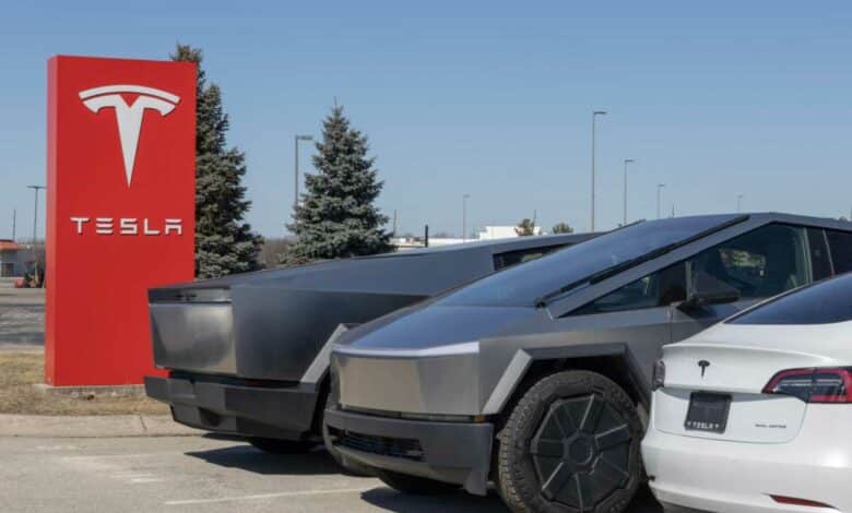 Des véhicules Tesla devant l'enseigne de la marque.