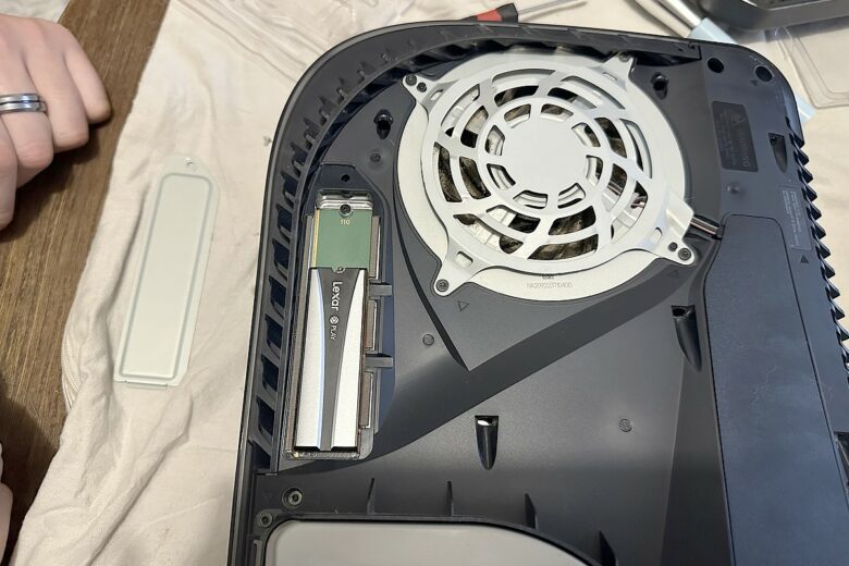 Insertion du Lexar Play 2280 SSD 4 To dans l’emplacement dédié de la PS5, juste à côté du ventilateur.