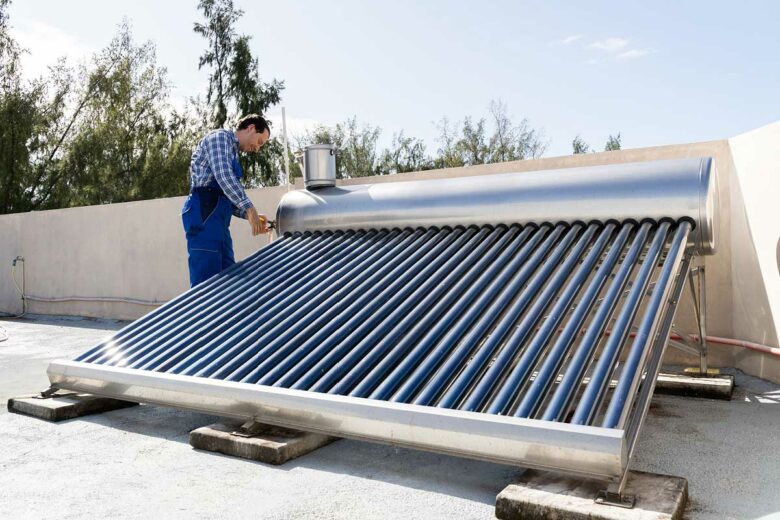 Un technicien installe un chauffe-eau solaire.